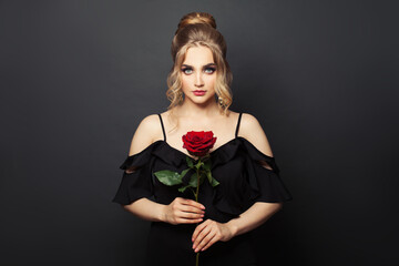 Beautiful passionate woman with red rose flower on black background