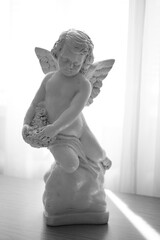 Statue of a cute angel with wings on the table. BW photo