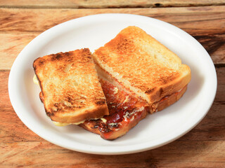 Two slices toast bread with butter and jam on white plate, selective focus