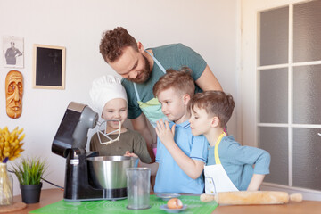 happy father with children cooks on paternity leave in the kitchen