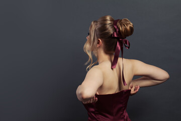 Beautiful woman putting on silky evening gown on black background