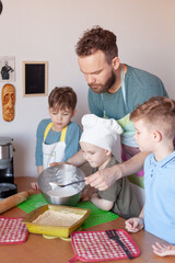 happy father with children cooks on paternity leave in the kitchen