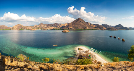 Panormaric view of Komodo islands, Indonesia, from top of hill with mountains in background and crystal clear sea in foreground