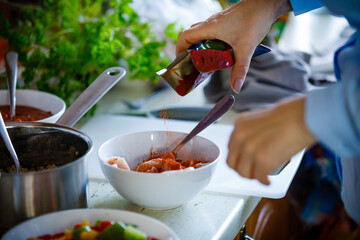 Woman seasoning chicken breast nuggets in bowl