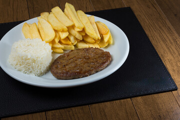 Combined dish with a tasty hamburger with rice and fries. Popular gastronomic photography.