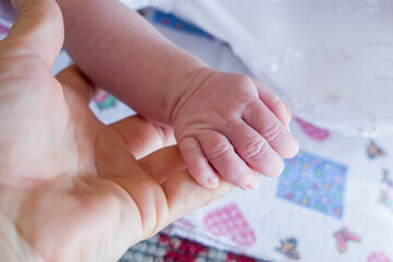 parent holding baby. 
Mom holds the hand of a newborn baby.