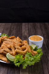 Breaded portion and fried fish served on lettuce leaves with lemons and tartar sauce to accompany. Gourmet photography with space for texts. Popular restaurants.