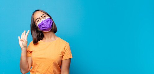young woman smiling and looking friendly, showing number four or fourth with hand forward, counting down