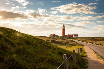 Iconic lighthouse surrounded by houses during sunset at the island of Texel, The Netherlands - obrazy, fototapety, plakaty