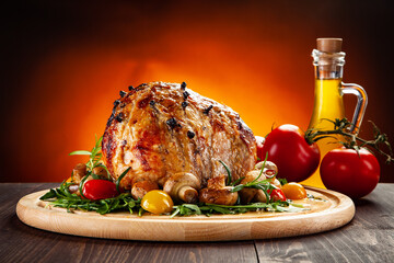 Roast whole pork ham with vegetables against orange gradient background