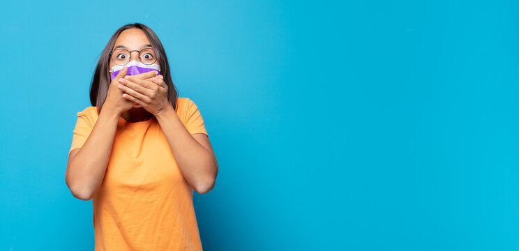 young woman covering mouth with hands with a shocked, surprised expression, keeping a secret or saying oops