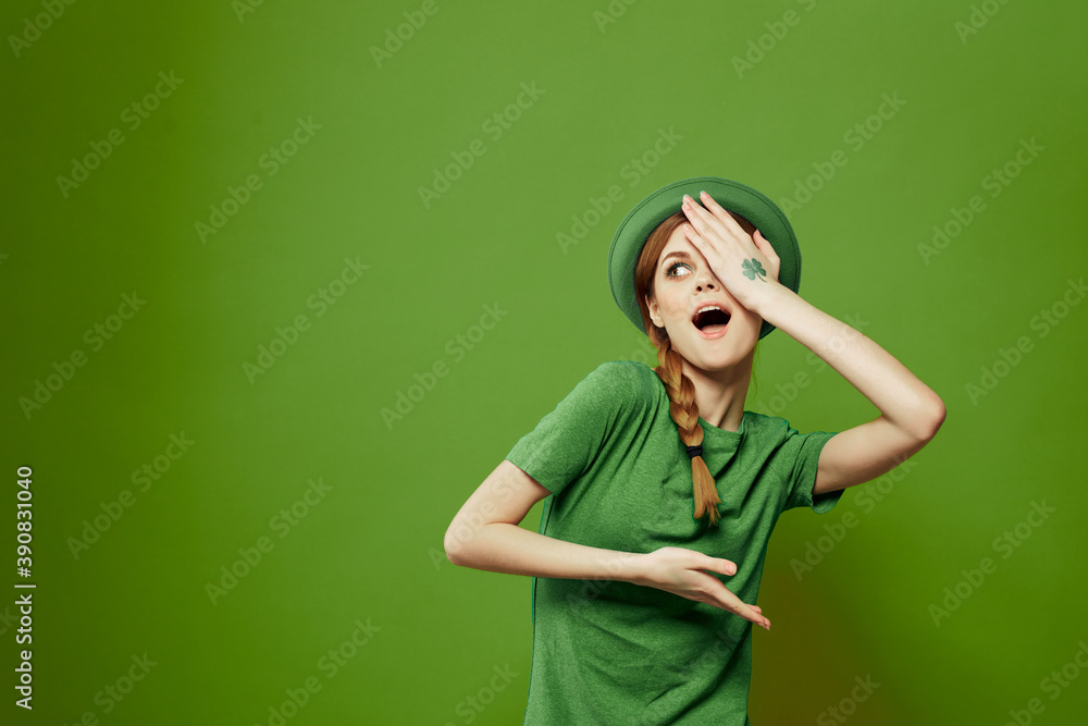 Wall mural happy woman with shamrock on st. patrick's day in green clothes and a hat on her head gesturing with