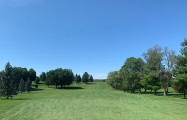 Fototapeta na wymiar A green golf course and blue sky on a beautiful summer day in Canada
