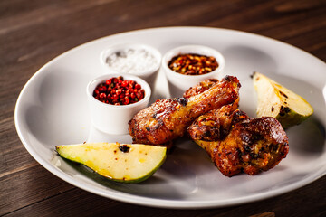 Barbecue chicken drumsticks with fried pear on wooden table
