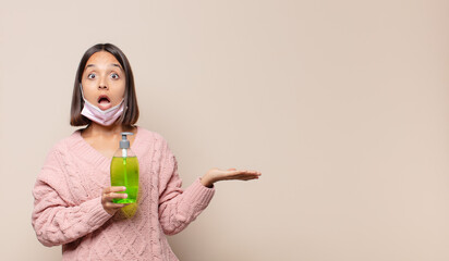 young woman looking surprised and shocked, with jaw dropped holding an object with an open hand on the side