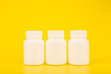 Three unbranded vitamin bottles on yellow background