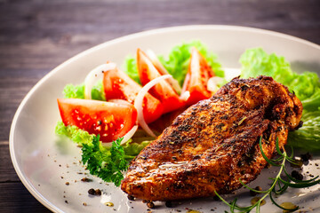 Fried chicken breast with boiled potatoes and fresh vegetables on wooden table
