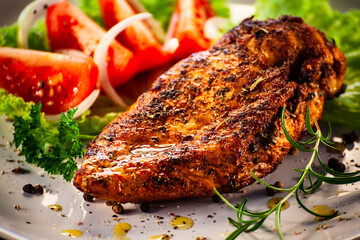 Fried chicken breast with boiled potatoes and fresh vegetables on wooden table

