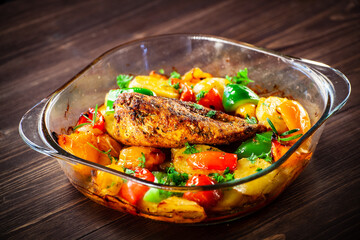 Roast chicken breast with potatoes and vegetables on wooden table