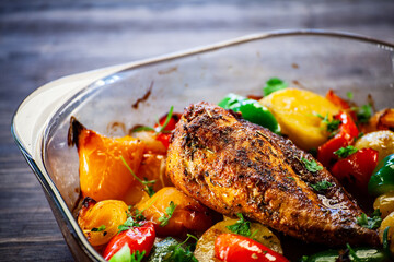 Roast chicken breast with potatoes and vegetables on wooden table