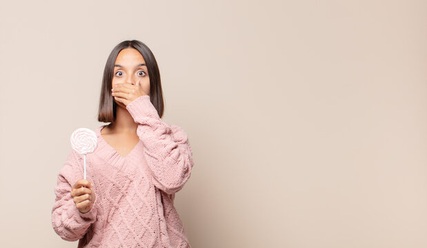 young woman covering mouth with hands with a shocked, surprised expression, keeping a secret or saying oops