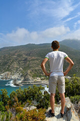 Naklejka premium Young man watching the bay of Marine di Giottani, one of the most remote beaches of the western side of Cap Corse, the northern peninsula of the island famous for its wild landscape. Corsica, France 