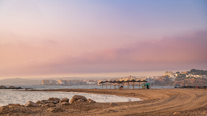 Woman keeping fit on the beach with Natural Beach parasols and sun loungers against the backdrop of the town of l'Escala