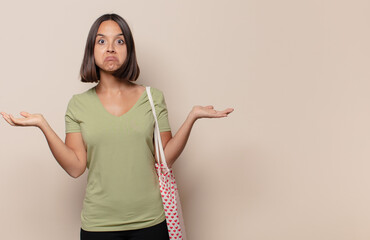 young woman feeling puzzled and confused, doubting, weighting or choosing different options with...