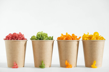 Multicolored pasta in a disposable kraft paper cups on a white background. Copy, empty space for text
