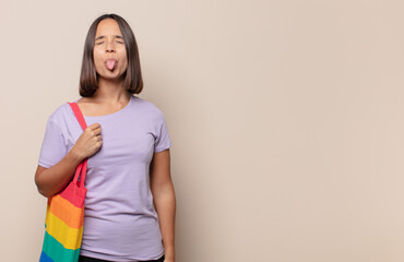 young woman with cheerful, carefree, rebellious attitude, joking and sticking tongue out, having fun