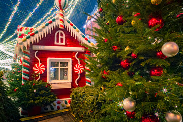 Christmas decorations in Moscow. Russia in winter. Russian hut next to Christmas tree. Celebrating new year in Russia. New Year's decorations in Russian cities. Festive events Moscow. Night Moscow.