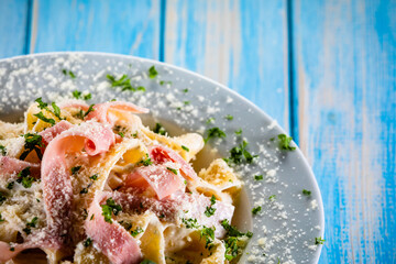 Pasta carbonara on white plate on wooden table
