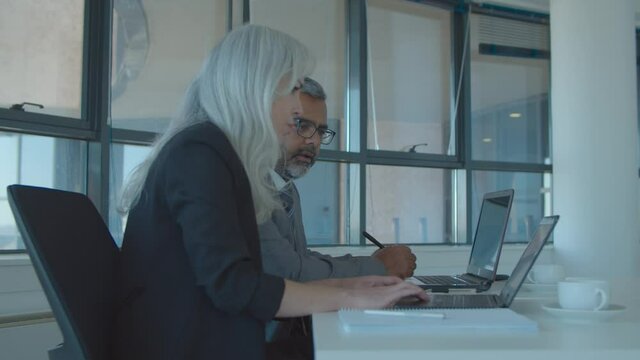 Company manager and executive watching and discussing content on laptop, pointing at screen and talking. Dolly shot. Businesspeople meeting concept