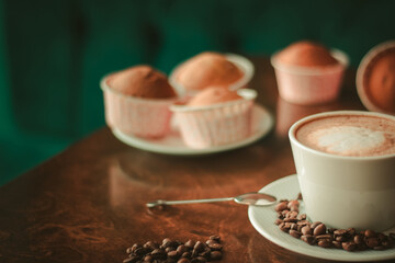 Coffee on wooden table close up in coffee shop , coffee beans and cupcakes around it