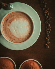 Coffee on wooden table close up in coffee shop , coffee beans and cupcakes around it