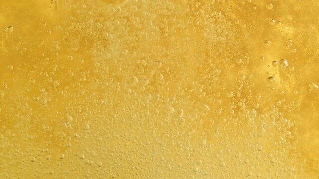 Super Slow Motion Detail Shot of Sparkling White Wine Bubbles on Golden Luxury Background at 1000fps.