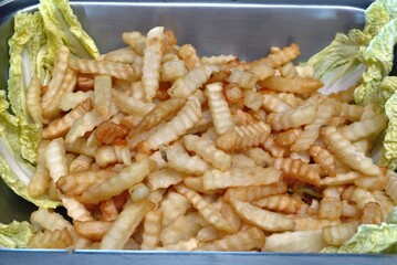 Tray of french fries on a bed of vegetables