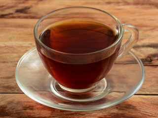 freshly brewed darjeeling black tea in glass cup on rustic wooden background, selective focus