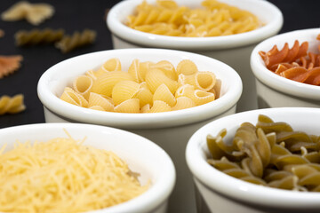 Group of bowls with assorted uncooked pasta