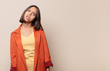 young woman feeling puzzled and confused, with a dumb, stunned expression looking at something...