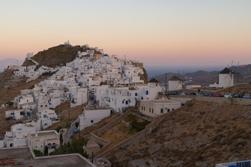 Fototapeta premium Serifos village, Serifos island, Greece. A view of the village after the sunset. Blue hour. White houses with Cycladic architecture, on the hill. The sea and the sky in deep blue and orange colors.