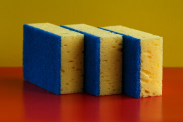 Close up of three big yellow sponges for washing on a colored background 