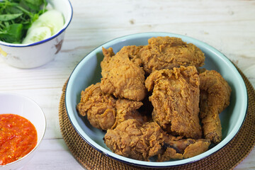 Close up view of fried chickens with golden shiny, crispy and oily textured. Served on ceramic grey plate with chili sause, garnished with basil leaves and lemon slices. Grey  wooden background.