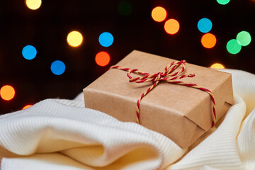 Christmas or New Year gift boxes on light cloth against a background of colorful lights. Close-up, selective focus