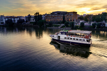 Barco de pasajeros por el río Guadalquivir en Sevilla como atracción de turistas al atardecer de...
