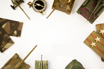Military concept. Background with old military compass, military chevrons and miniature toy tanks on white background, free space for text in the center, without people. Overhead view
