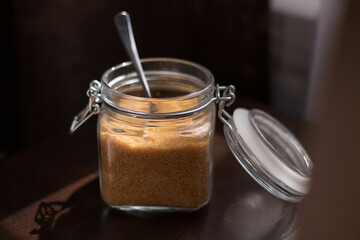 Transparent glass jar with brown sugar cane on a black background