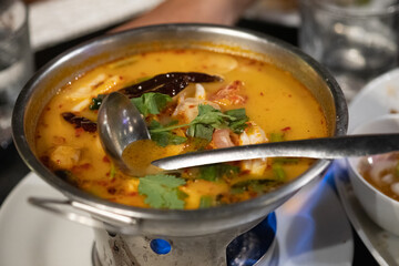 Tom Yum kung with herb on hot pot. Spicy Thai traditional food