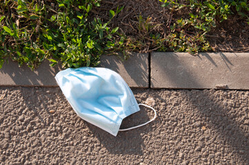 a medical mask thrown away on the sidewalk in the street. High quality photo