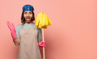 young woman housekeeper feeling happy, excited, surprised or shocked, smiling and astonished at...
